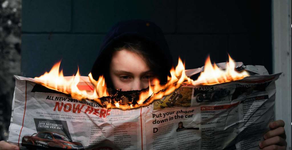 Man reading burning newspaper